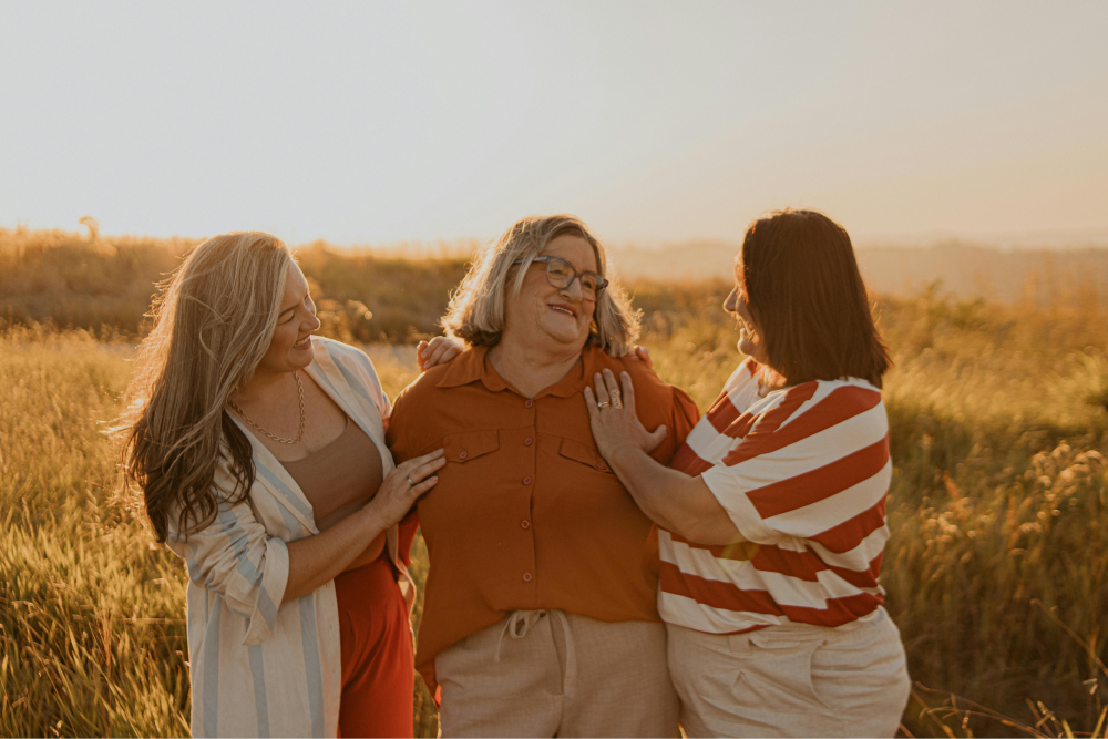 Three cheerful women stand in a field.