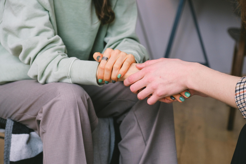 A warm scene of connection as one woman holds another's hand, offering comfort and a sense of welcome.