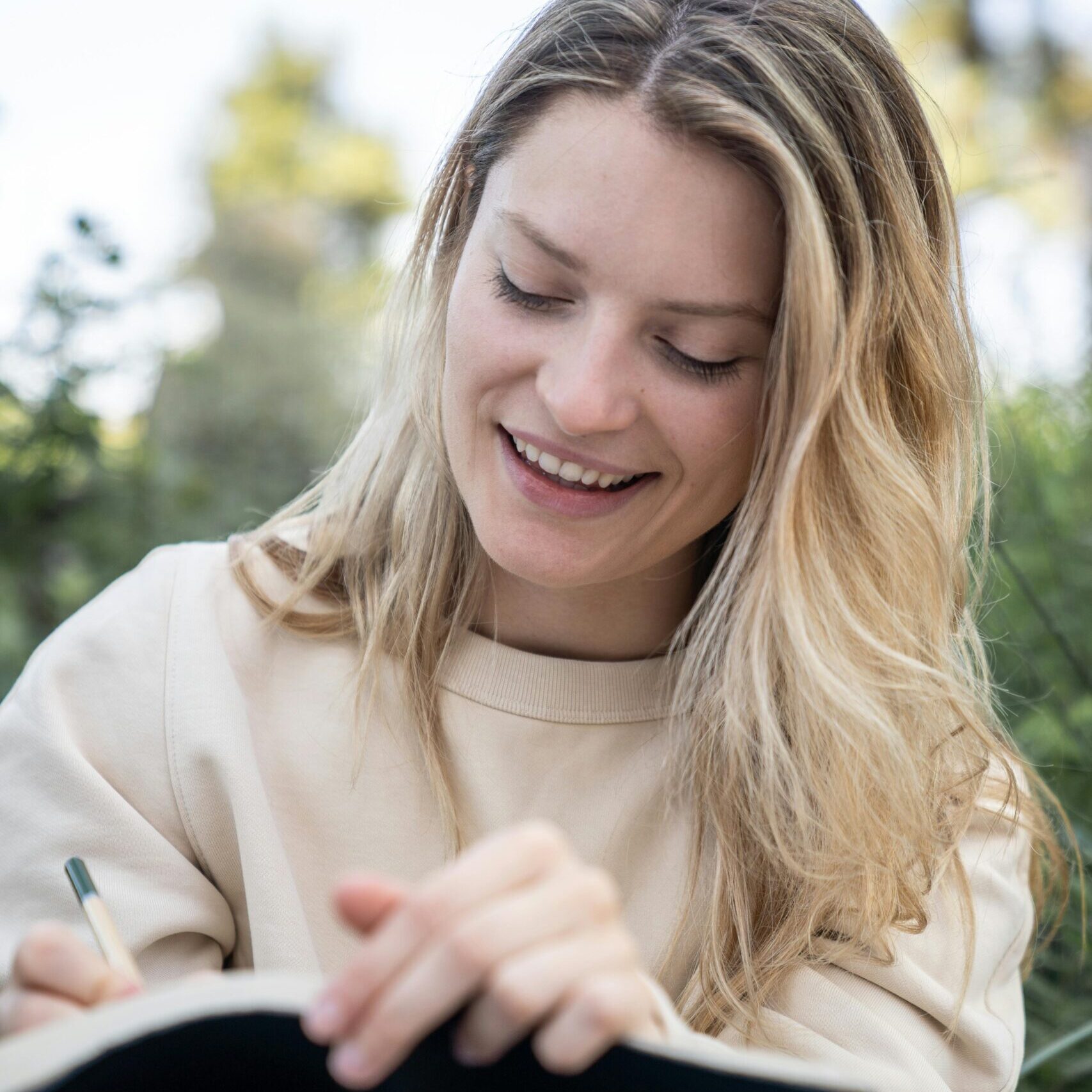 A woman on a bench writes in her journal, contemplating her progress and recovery goals.